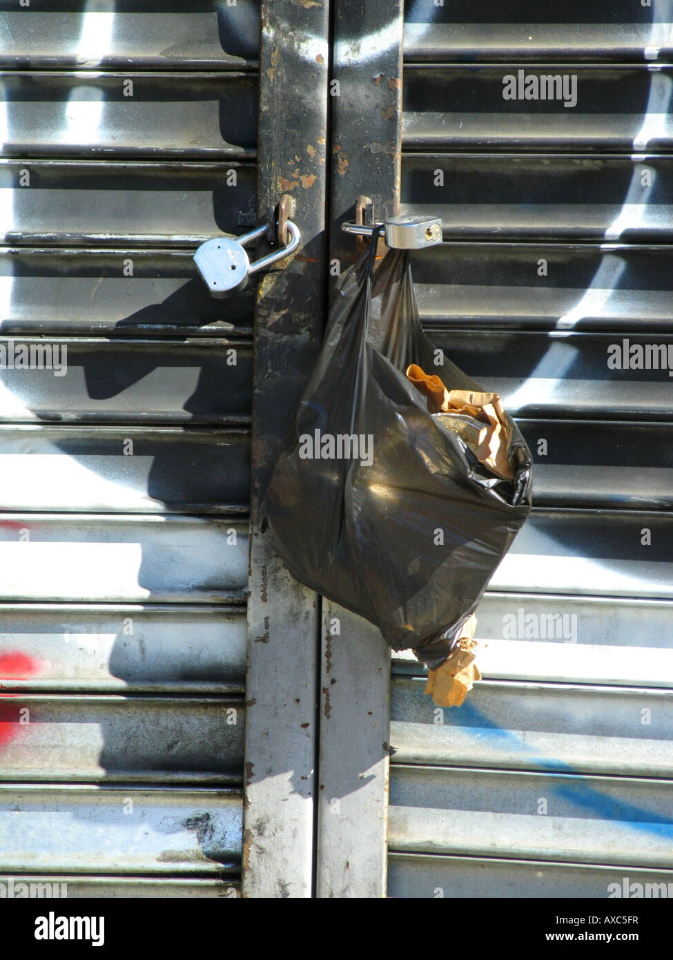 Garbage bag hanging on sprayed shutter of a closed shop at 125th street, USA, Manhattan, Harlem, New York Stock Photo