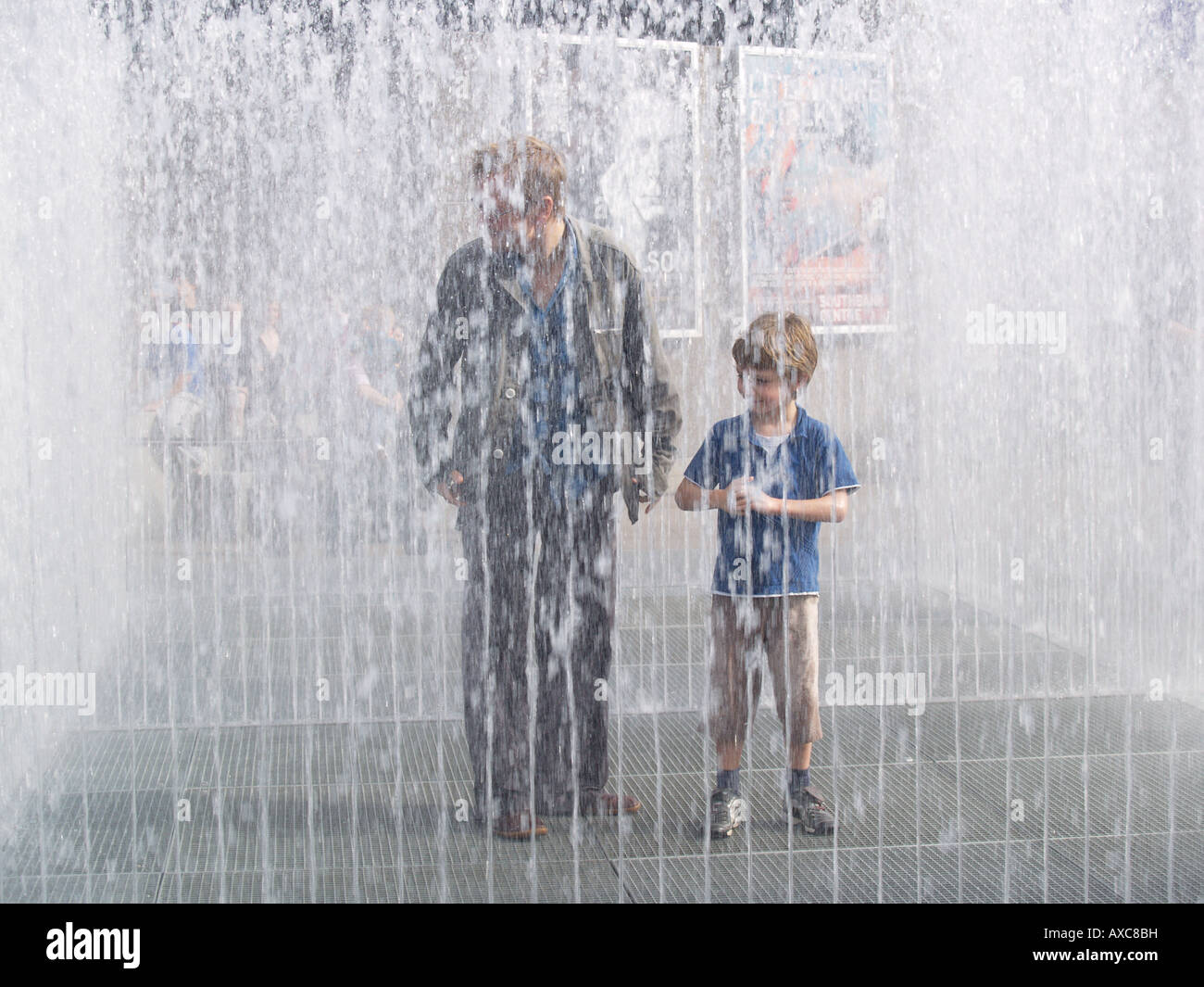 father and son in waterwall water fountain squirts southbank river thames london Stock Photo