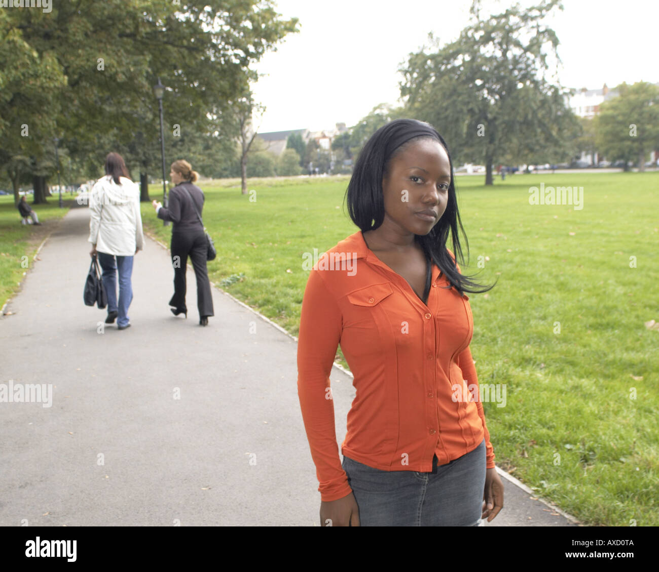 African female in early twenties on Clapham Common with two blurred non model released women Stock Photo
