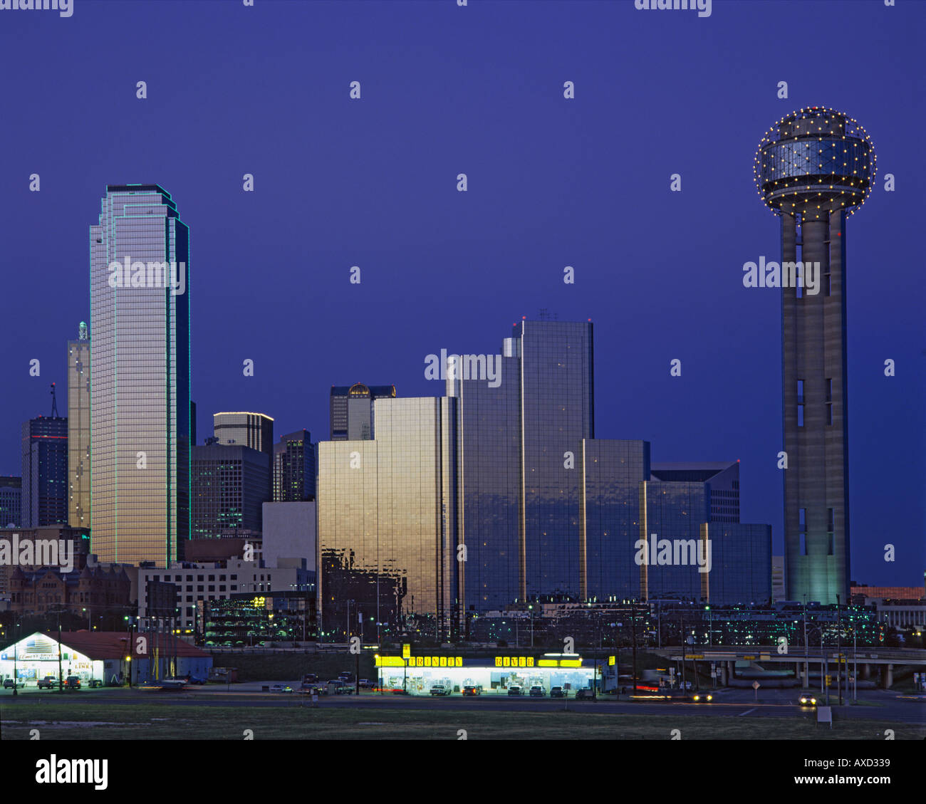 Cityscape of modern Dallas at sundown with lights on against dark blue