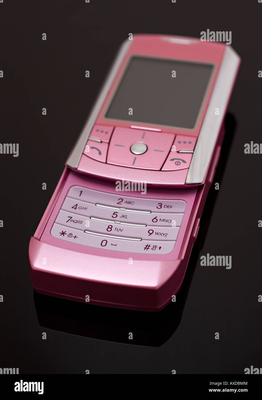 Pink mobile slider phone on a plain black background - no logo visible Stock Photo