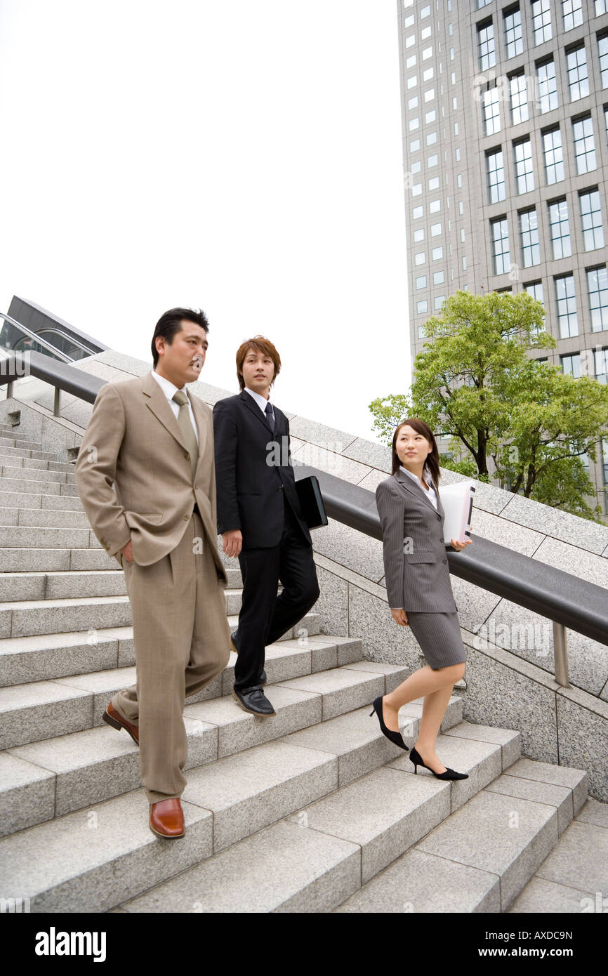 Three business people descending steps Stock Photo