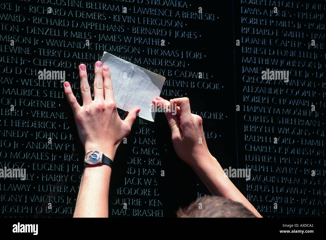 Man using coin to make paper rubbing of names engraved on the Vietnam