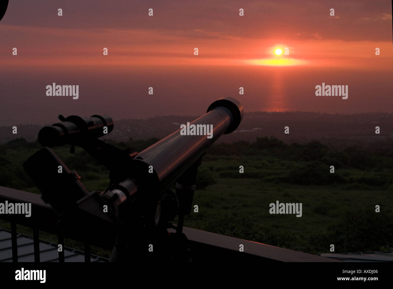 Aiming for the Sunset: A small telescope perched high above the Kailua Kona coast is aimed at the warm red glow of a setting sun Stock Photo