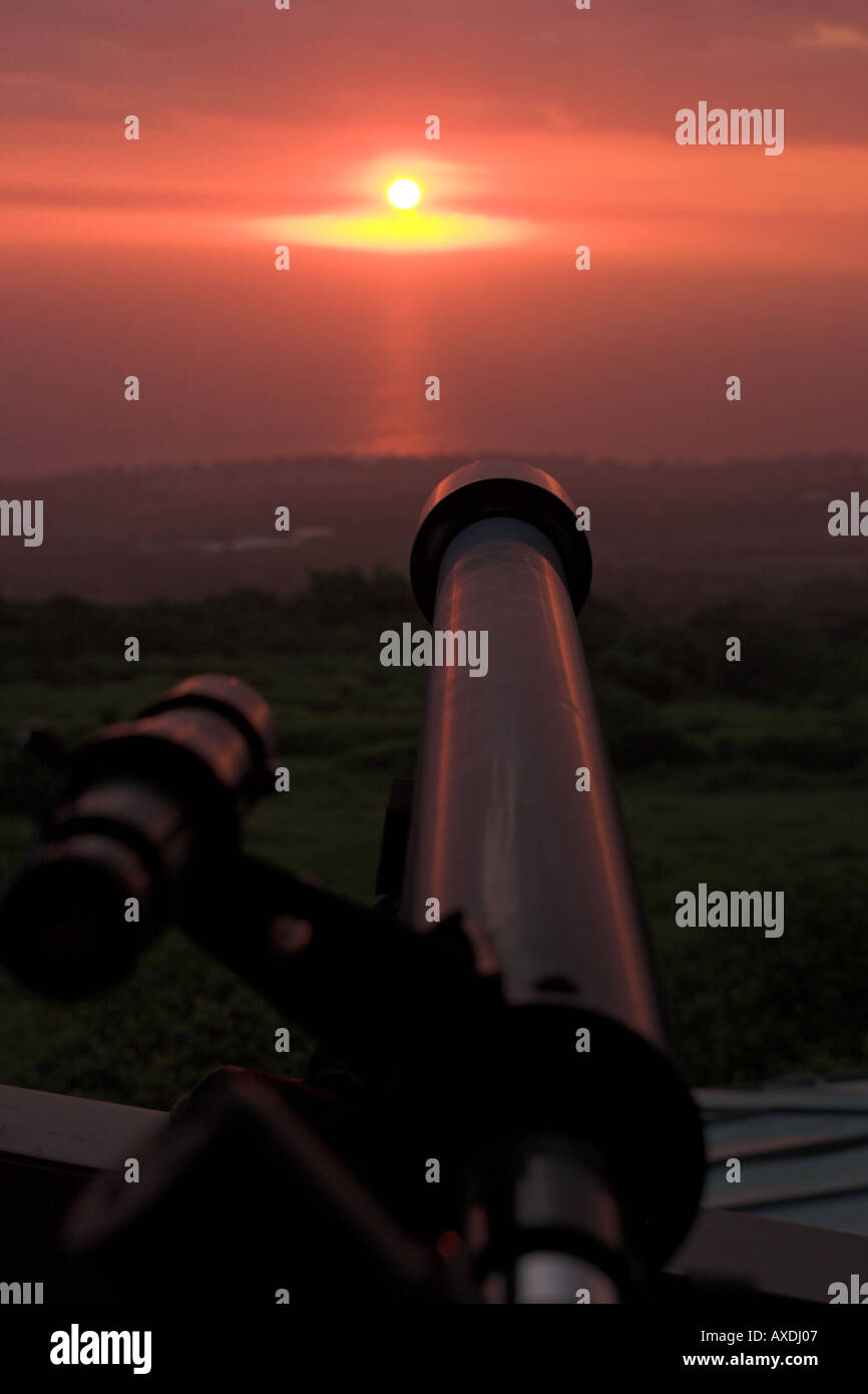 In the Sights: A small telescope perched high above the Kailua Kona coast is aimed at the warm red glow of a setting sun Stock Photo