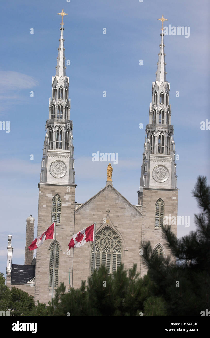 Canadian Basilica: The twin towers of the basilica shine in the afternoon sun Two Canadian flags fly in the foreground Stock Photo