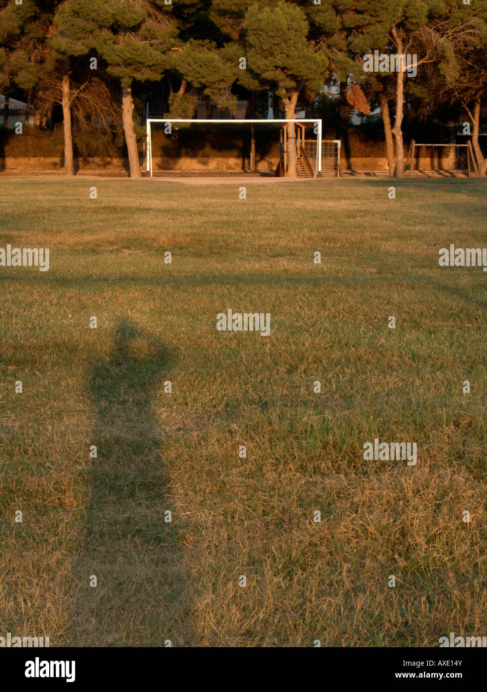 Shadow of a photographer in an empty football field at sunset Stock Photo