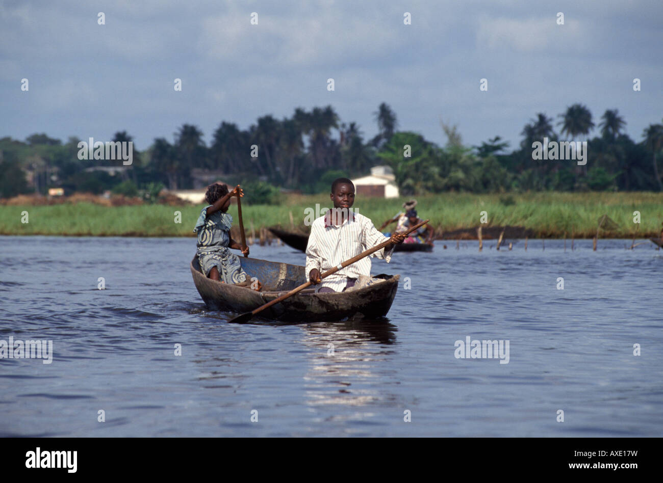 African boy and girl paddling Lake Nokoue in wooden canoe , Ganvie , Benin Stock Photo