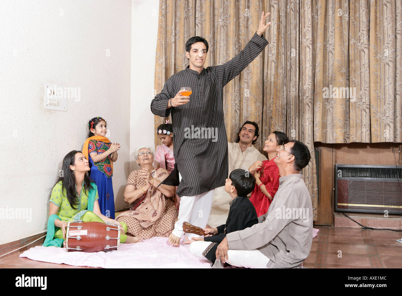 Man dancing with his family sitting around him Stock Photo