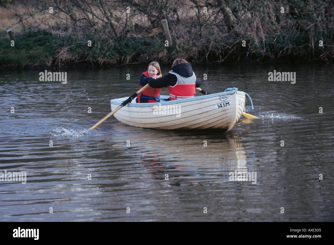 UK NORFOLK BROADS TWO GIRLS IN A ROWING BOAT WITH LIFE JACKETS WATER LAKES HOLIDAY LEISURE FUN SAFETY Stock Photo
