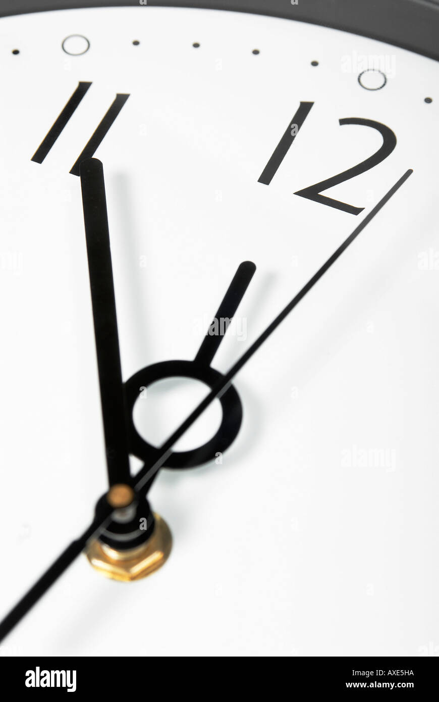 A wall clock shows five minutes before twelve, symbol for date, deadline, term Stock Photo