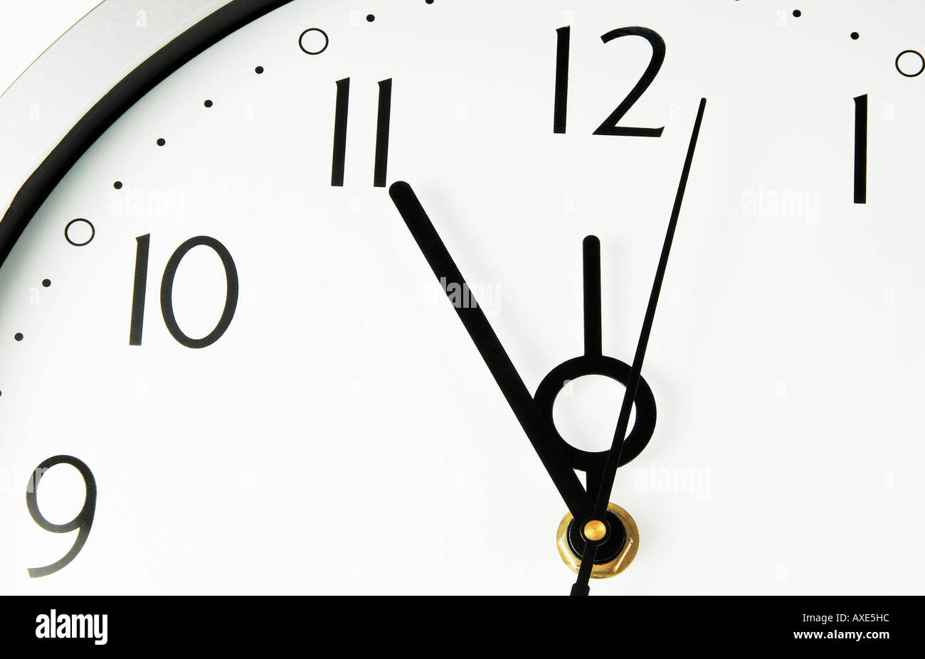 A wall clock shows five minutes before twelve, symbol for date, deadline, term Stock Photo