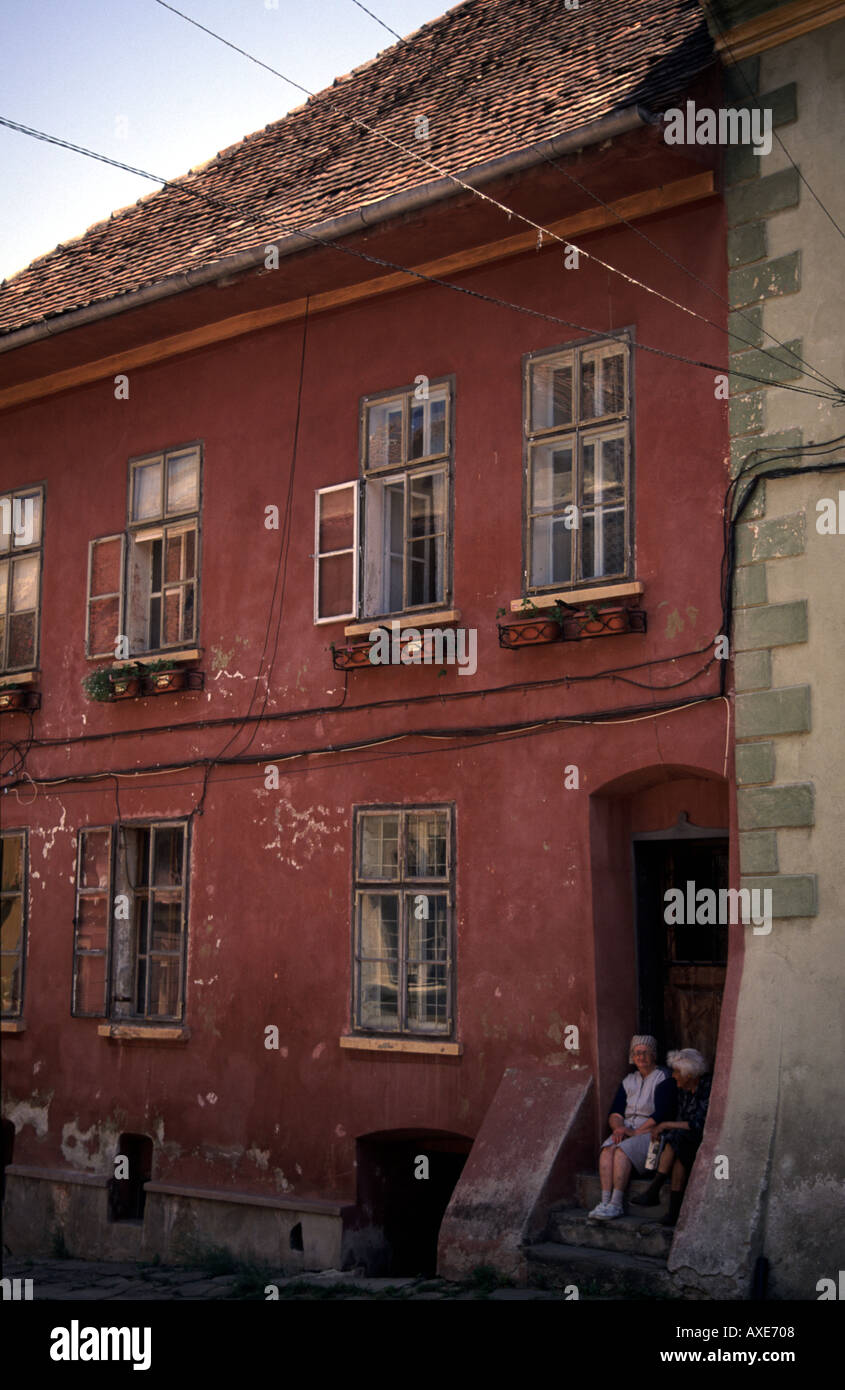 Locals gossip on the steps of a house in Sighisoara Transylvania Romania Stock Photo