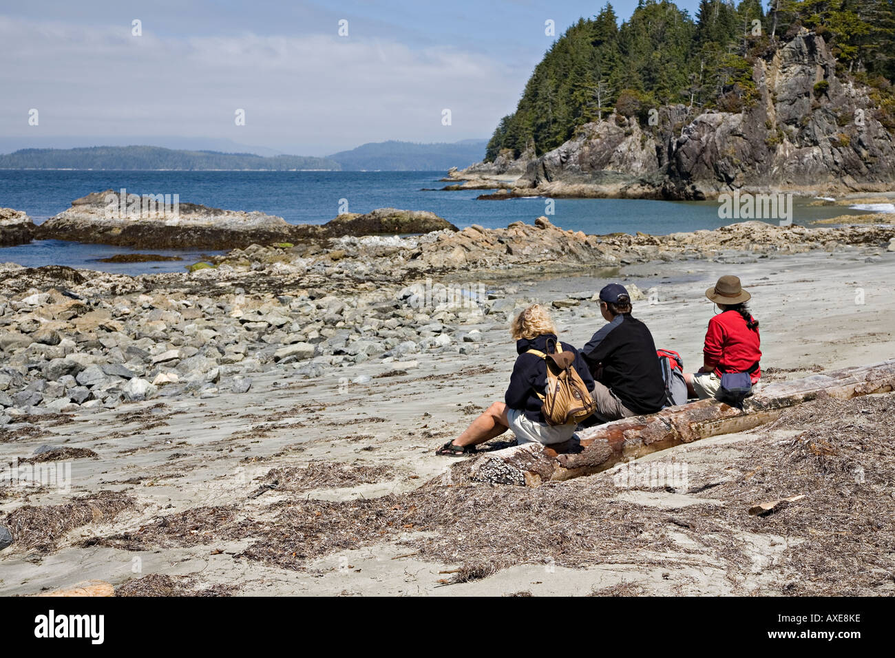 Three people sitting on beach Bamfirth west coast of Vancouver island Canada Stock Photo