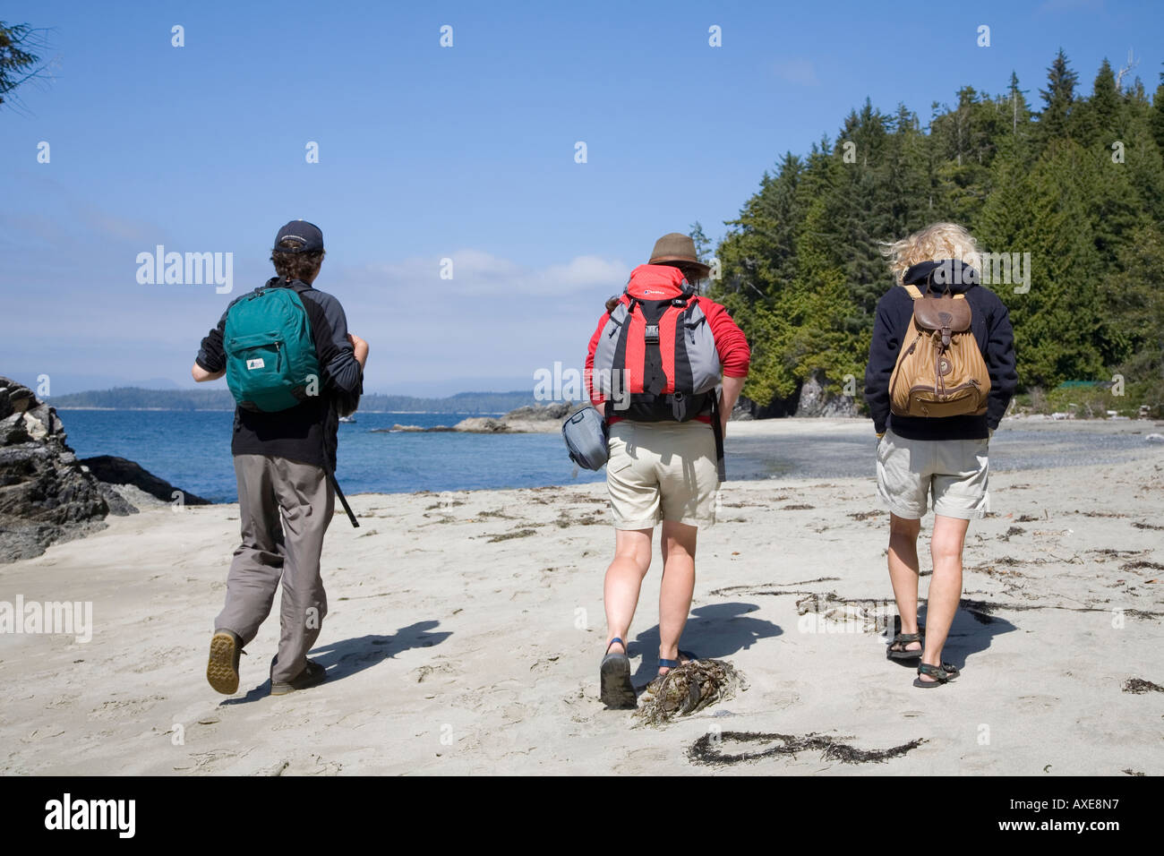 Three people walking on Brady beach Bamfirth west coast of Vancouver island Canada Stock Photo