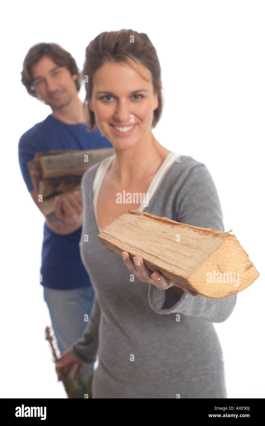 Woman holding log, man in background Stock Photo