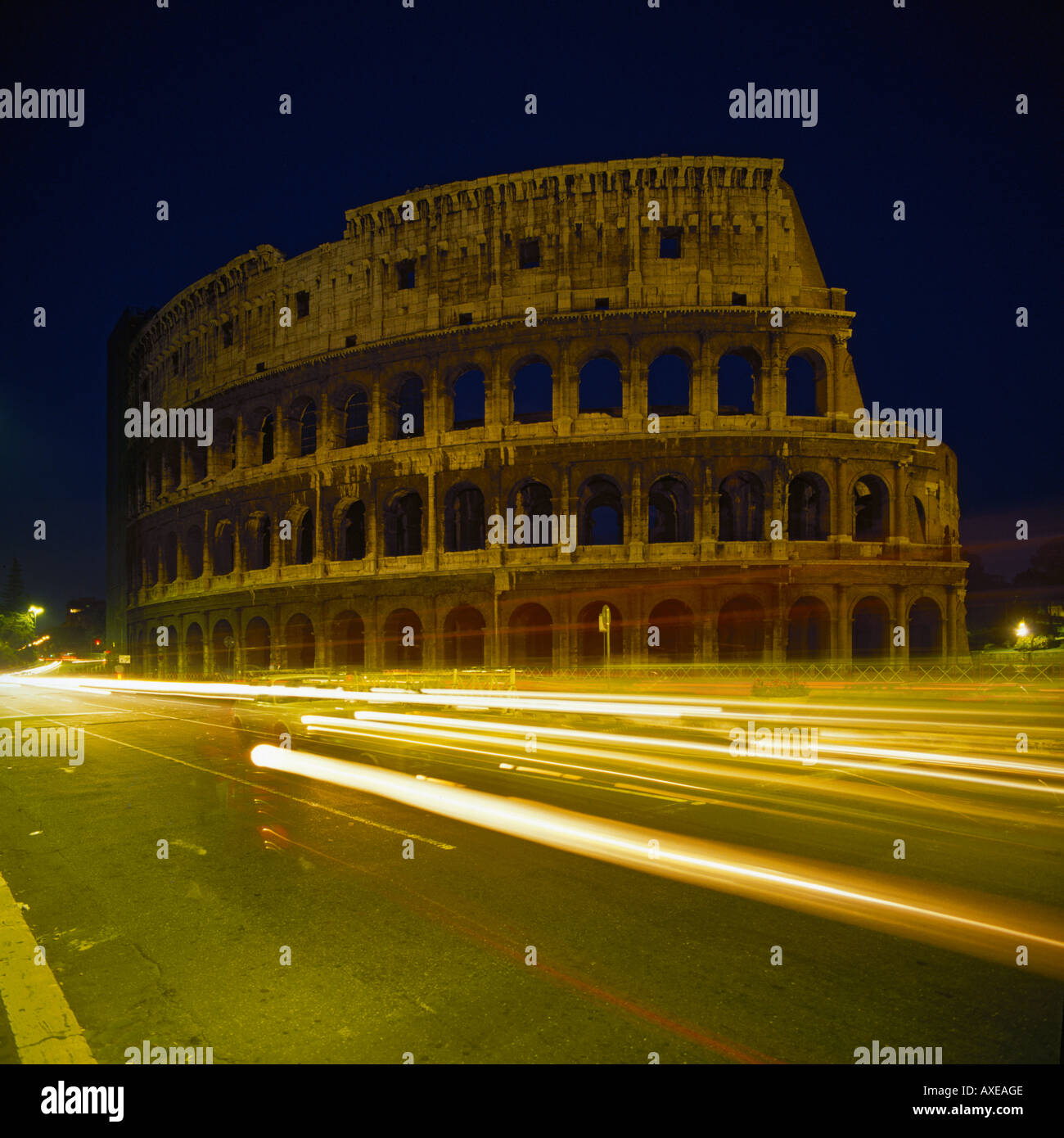 Section of the Colosseum at night with the lights of passing traffic drawing lines across the photo Rome Italy Stock Photo