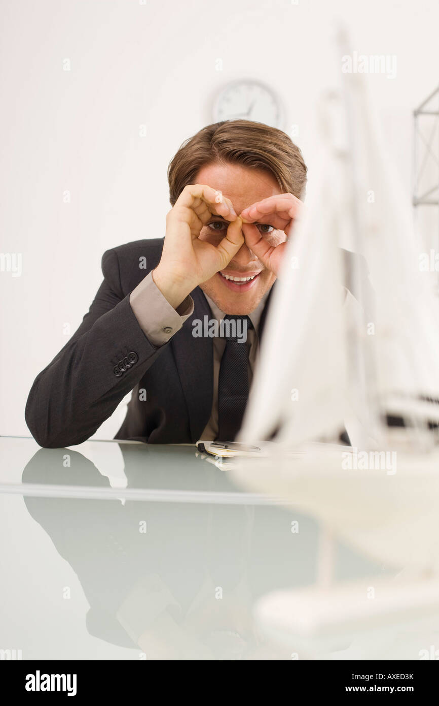 Businessman peering at model ship, portrait Stock Photo