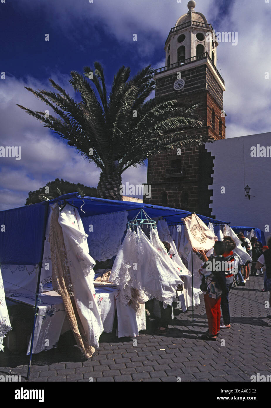 dh  TEGUISE LANZAROTE Sunday market  lace stall and church clock tower bazaar Stock Photo