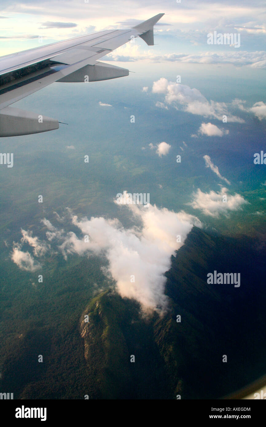 Hazy aerial overhead bird's-eye-view of mountains from aircraft flying over clouds Stock Photo