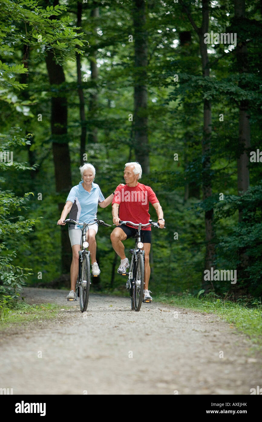 Senior couple biking on forest track Stock Photo