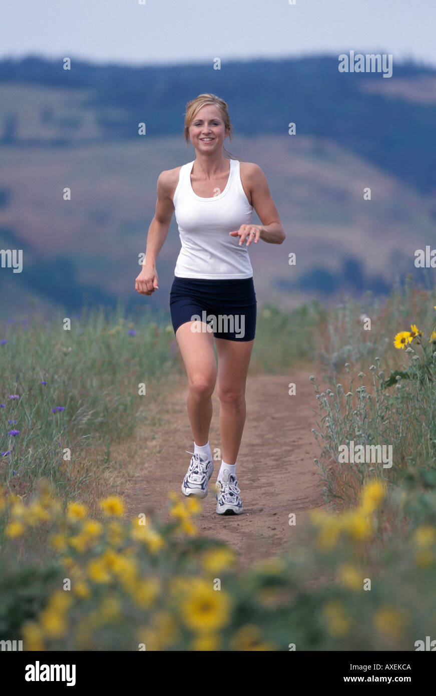 Woman Running on Dusty Trail Through Meadow Stock Photo