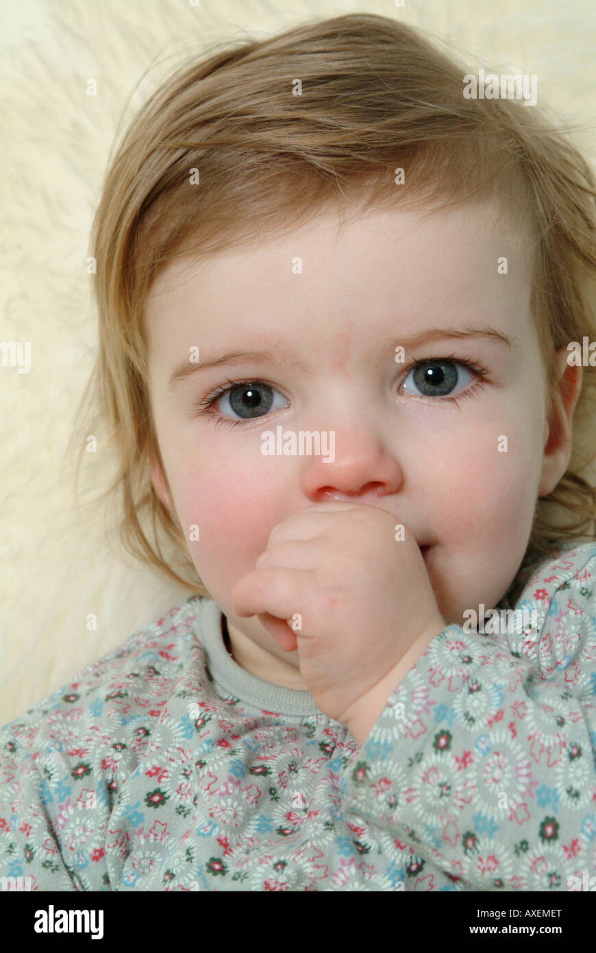 Little girl sucking her thumb and looking at the camera Stock Photo