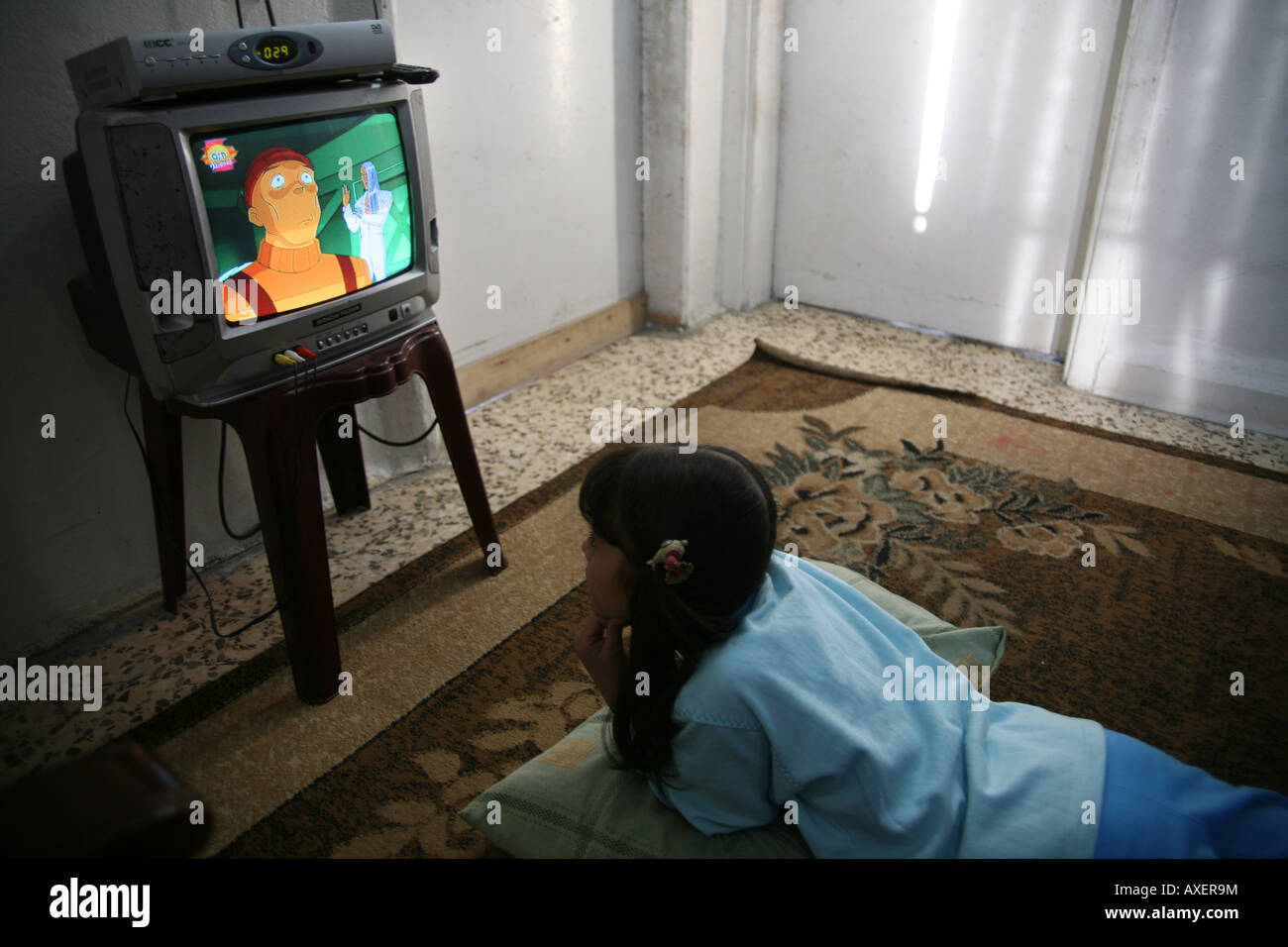 An Iraqi girl watches television at home Many Iraqi refugees have settled in Amman Jordan because of the ongoing violence in the Stock Photo