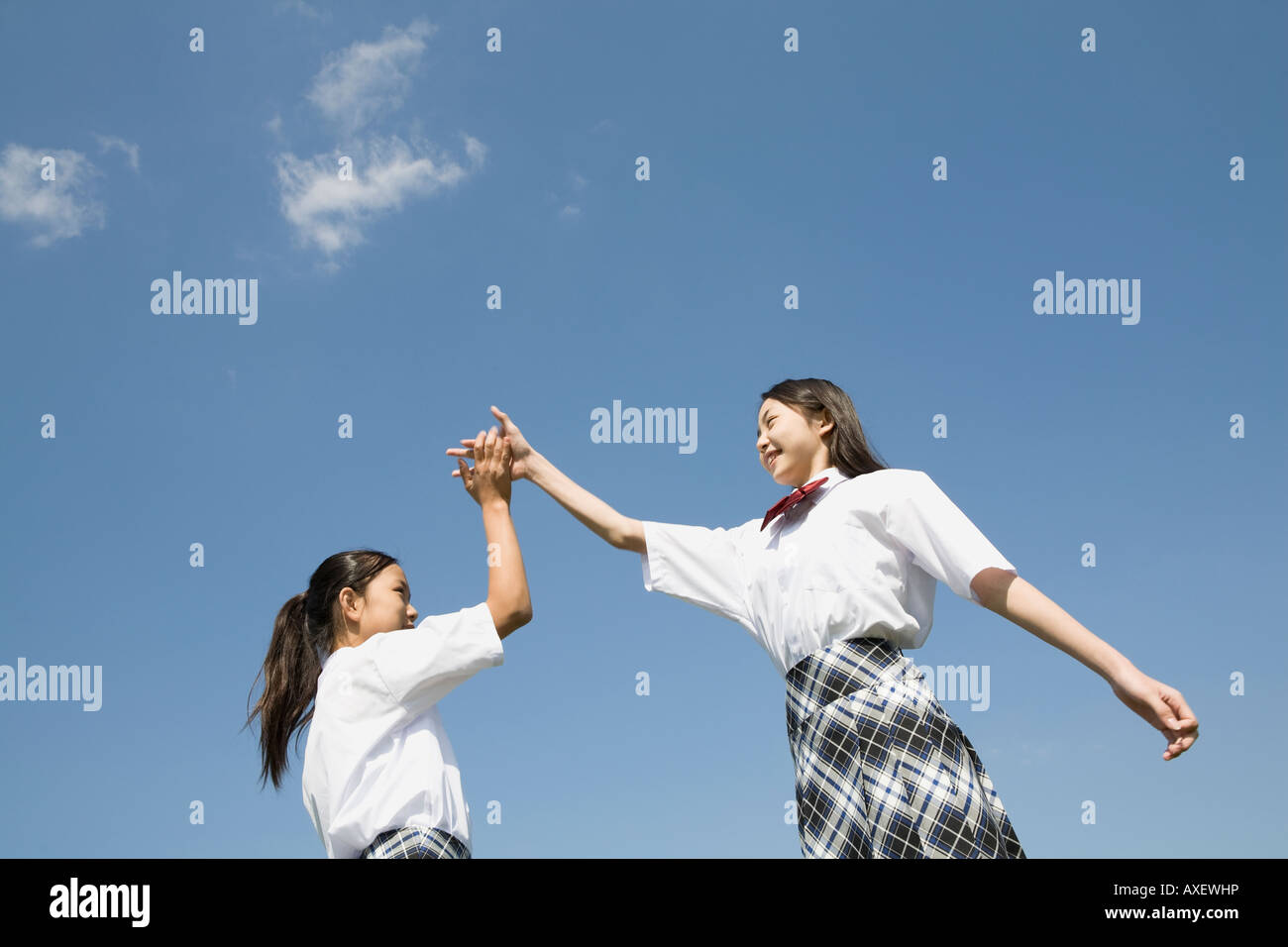 Two schoolgirls doing high-fives Stock Photo