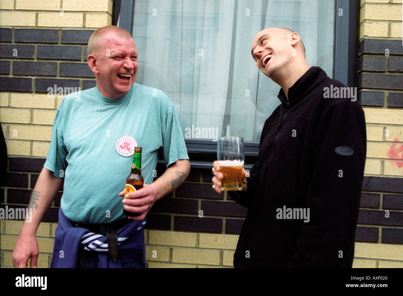 Two men outside pub drinking and laughing. Stock Photo