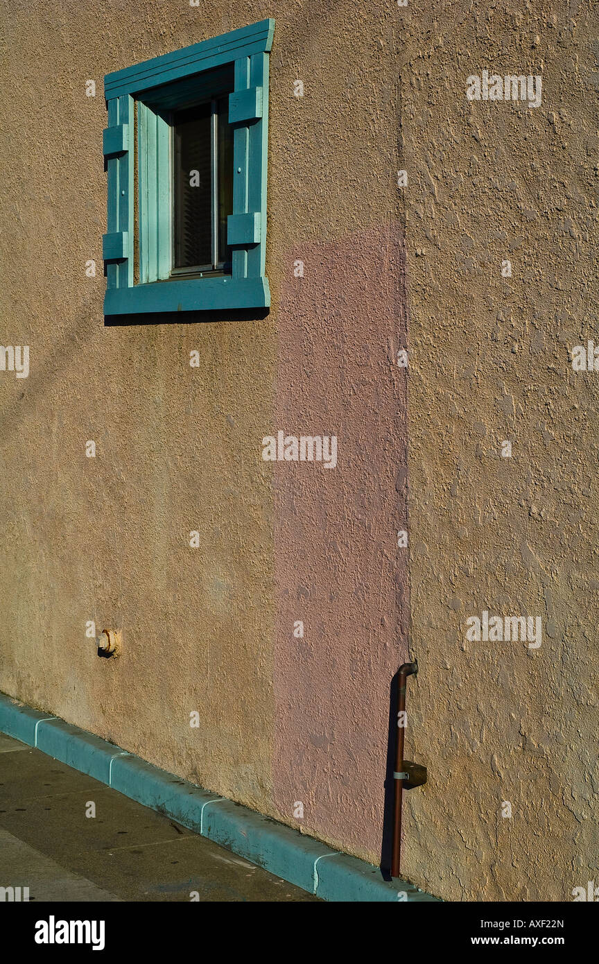 Turquoise colored wood frame around window in tan stucco wall Stock Photo