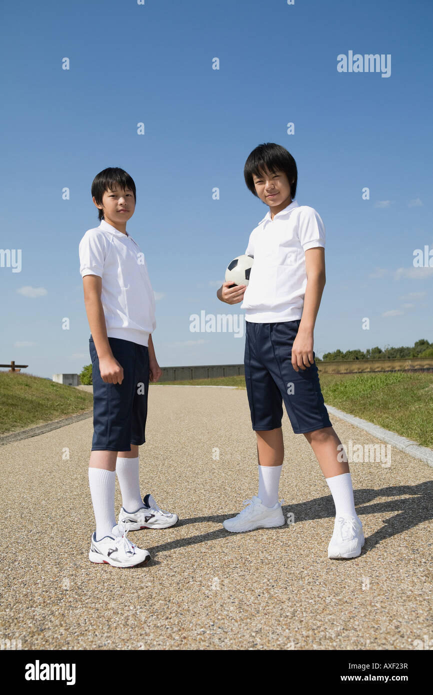 Two schoolboys standing with soccer ball Stock Photo
