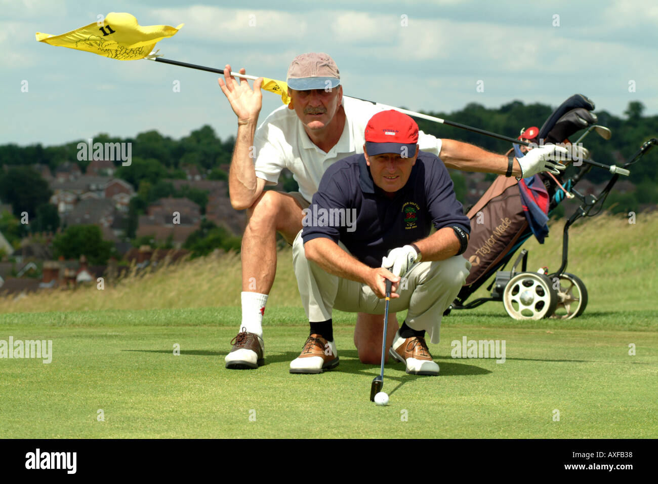 Senior Golfer with Caddie giving advice on a green on Andover Golf Course Hampshire England UK Europe Stock Photo
