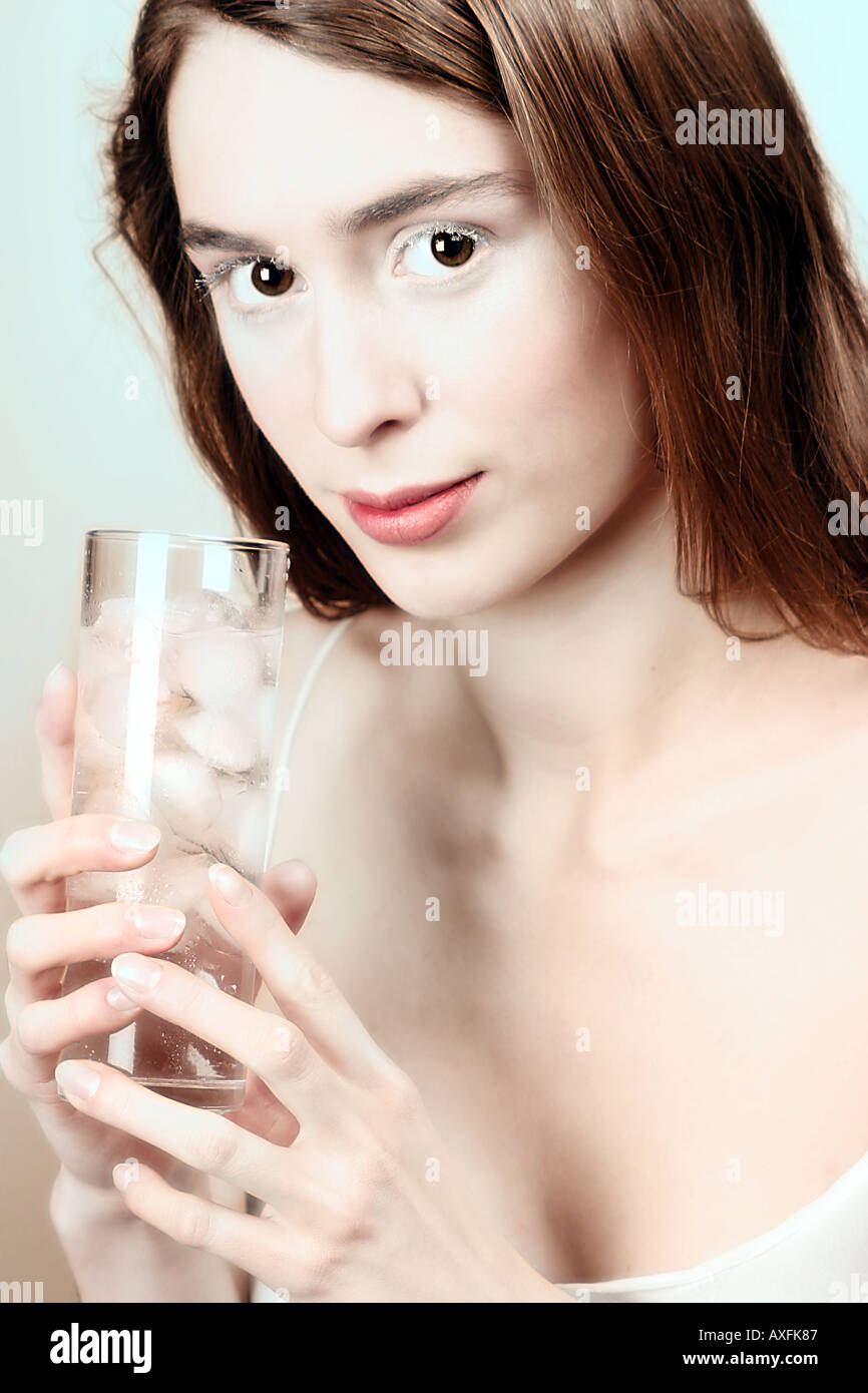indoor studio close up woman girl 20 25 young brunette long hair smile smiling hold glass drink water rock rocks ice drink aw Stock Photo