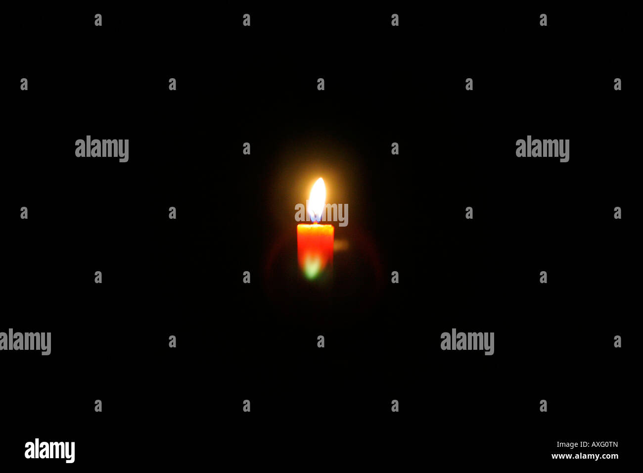 Lighting up the darkness - a candle in the dark Stock Photo