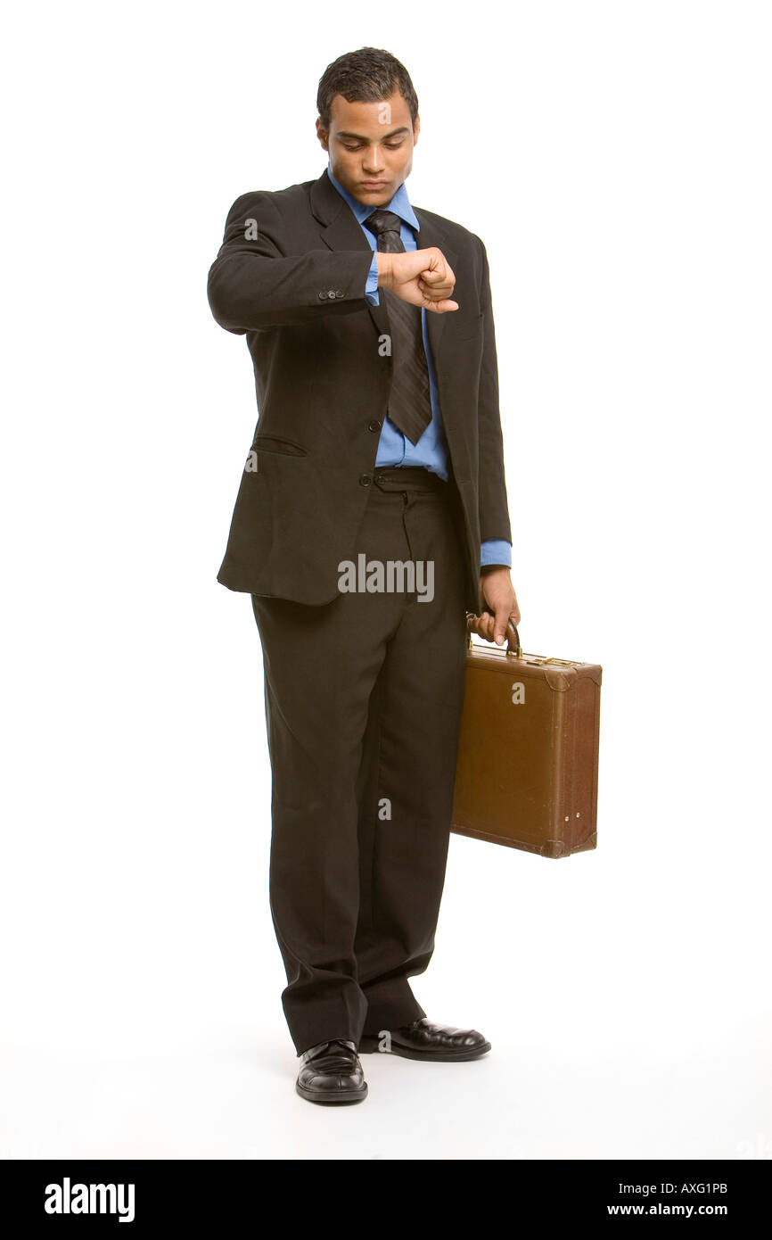 Young executive wearing a suit and carrying a brief case checking his watch with some impatience Stock Photo