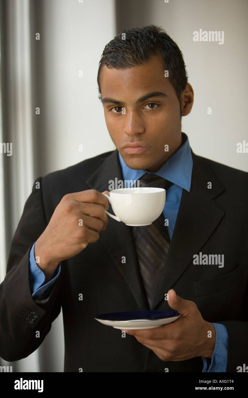 Serious young business man wearing a suit and holding a cup and saucer ...