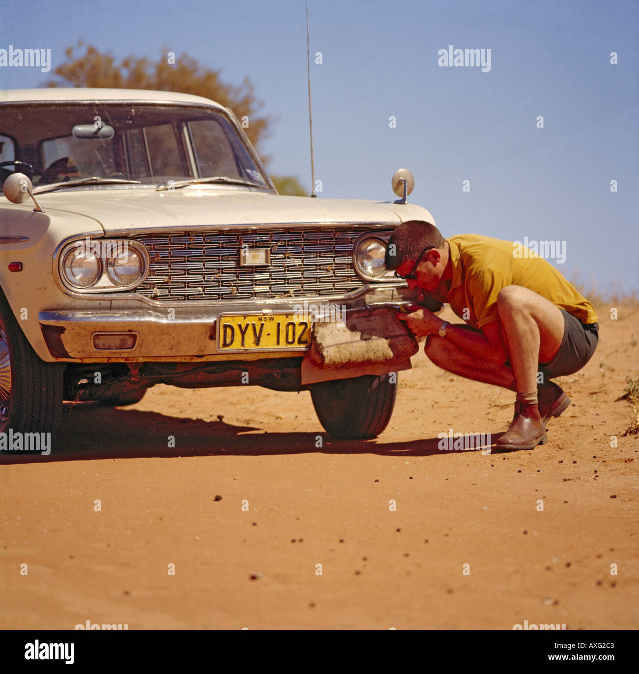 Driver drinking water from a waterbag cooled by slow evaporation and hanging from bumper of Toyota Crown Auto Australian outback Stock Photo