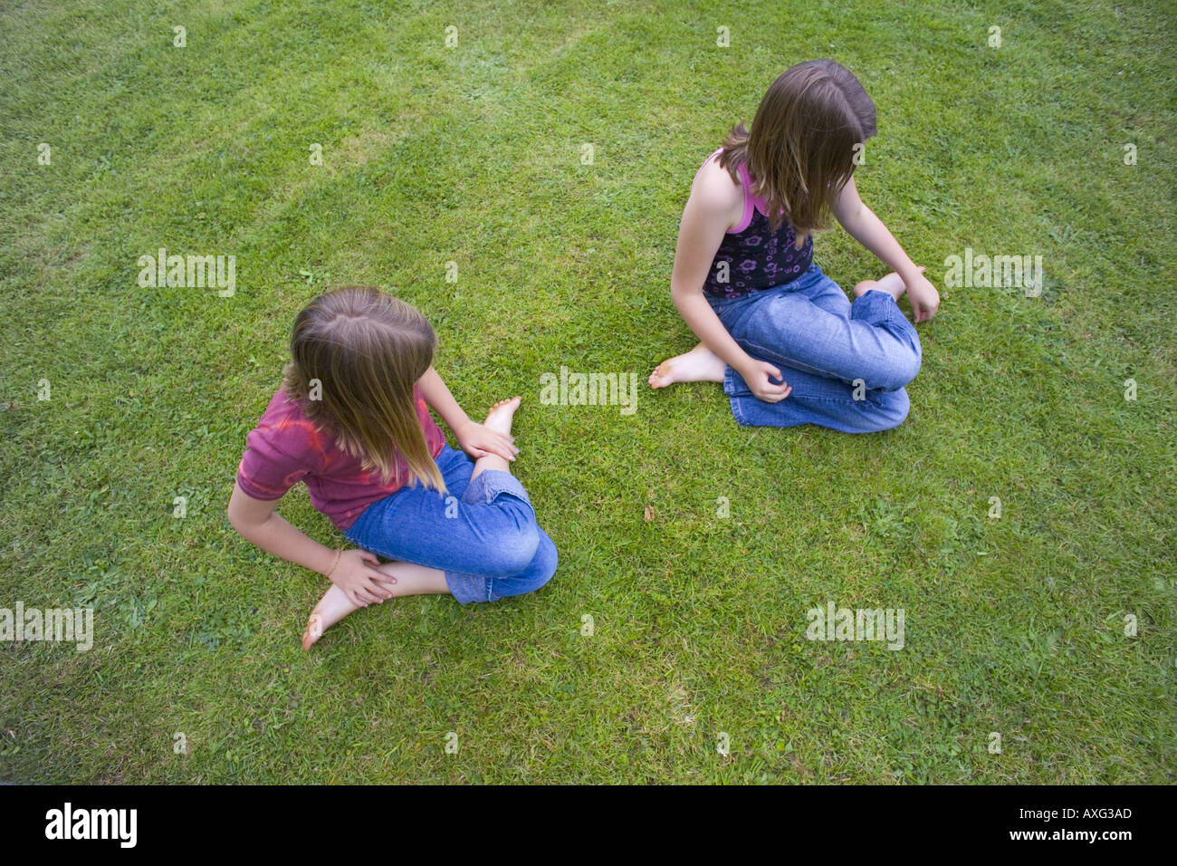 Uk Cornwall Two 9 12 Year Old Girls Sitting Cross Legged On Grass Lawn