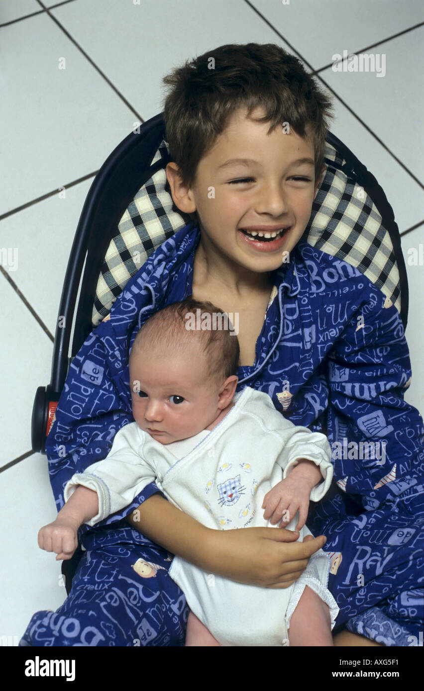 Portrait of a happy boy holding his new baby sister for the first time. Stock Photo