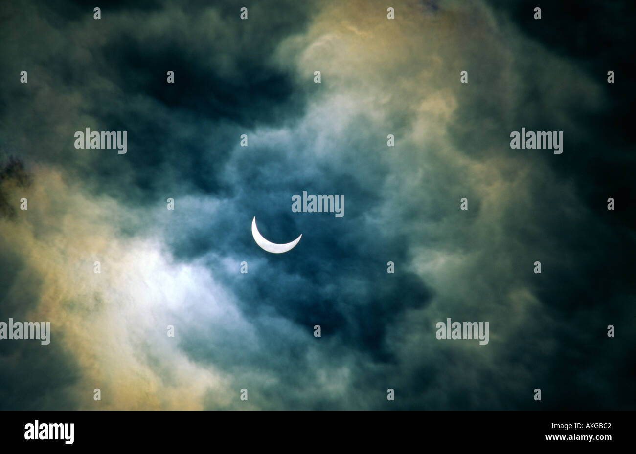 Solar eclipse. Moon passing in front of sun approaching full eclipse.  Romantic atmosphere veiled by thin stormy clearing cloud Stock Photo