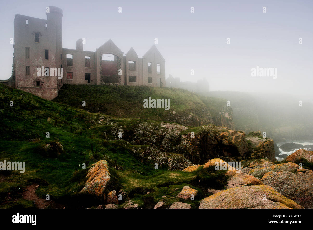 Moody Slains Castle north of aberdeen, scotland on a misty autumn day with steep cliffs and moody seas in foreground Stock Photo
