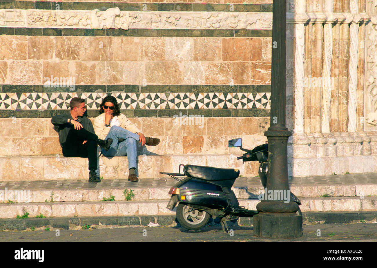 Messina Cathedral, Sicily, Italy. Two young local men youths teenagers with moped scooter on steps of west façade Stock Photo