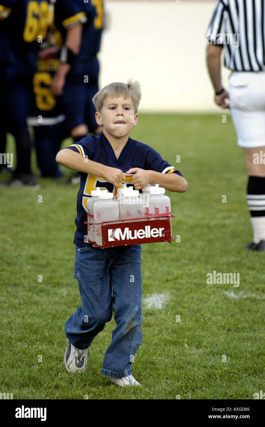 7 year old boy serves as a water boy helper during a high school football contest Stock Photo