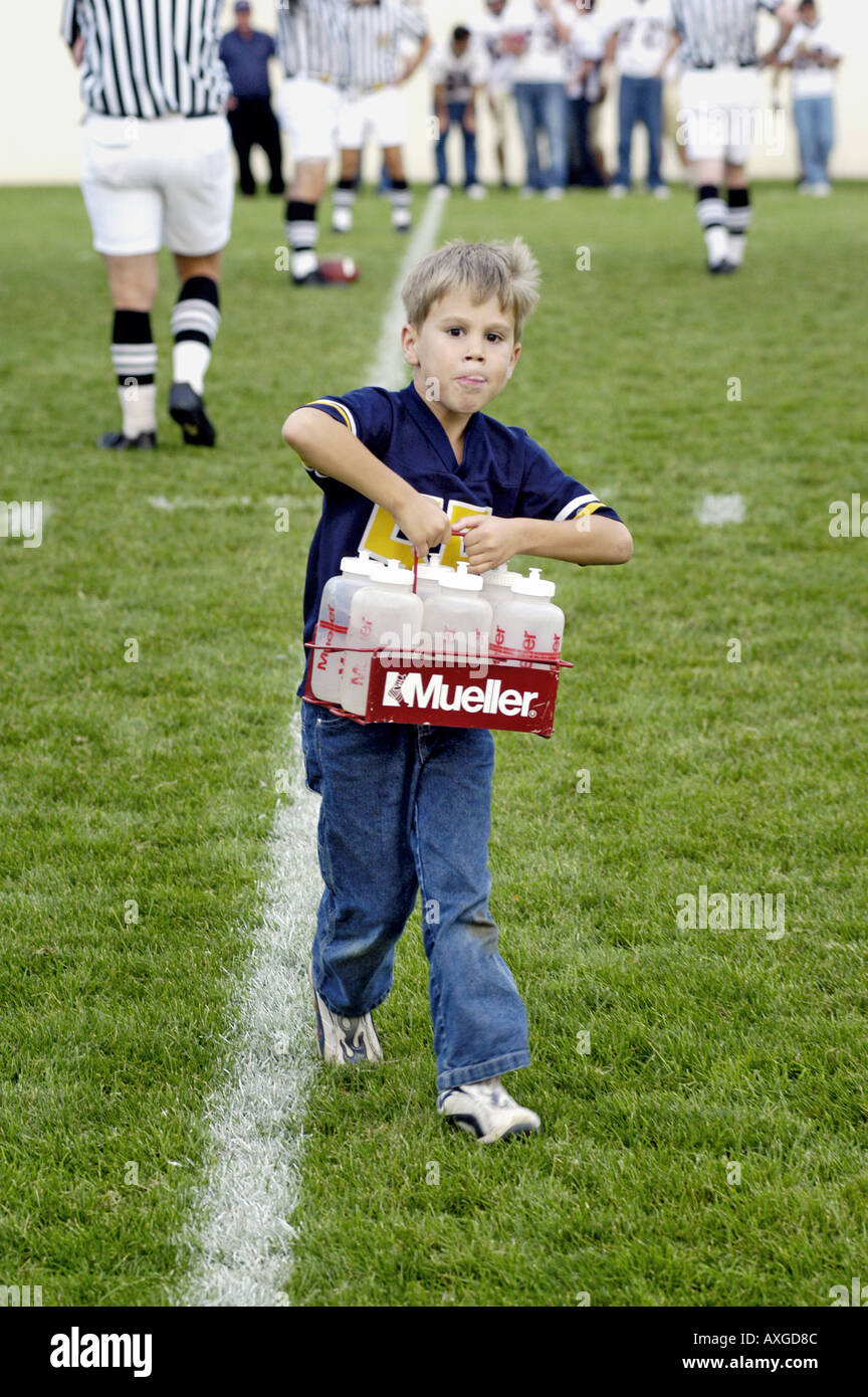 7 year old boy serves as a water boy helper during a high school football contest Stock Photo
