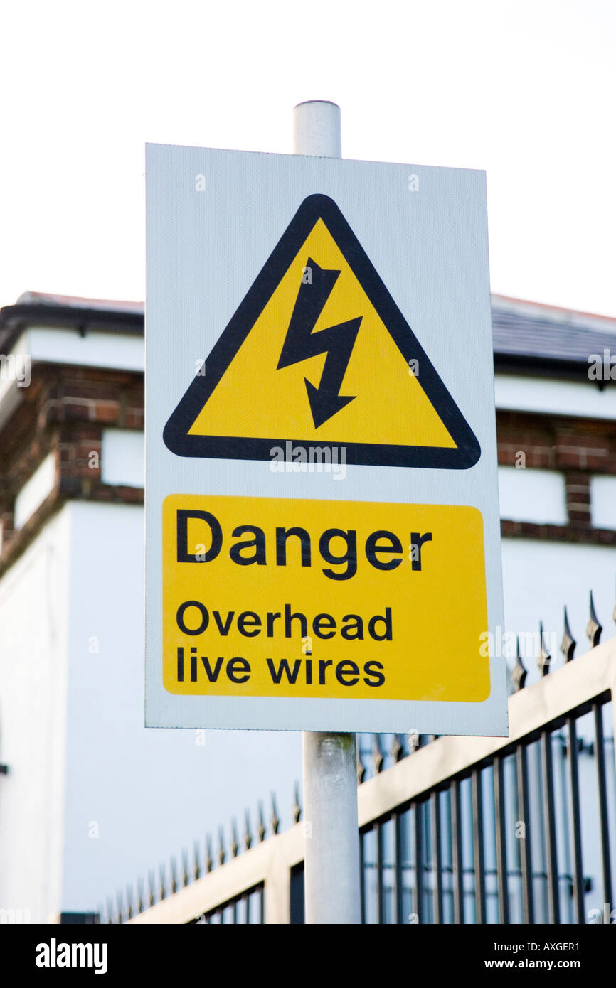 warning sign for high voltage overhead cables along a railway track in UK Stock Photo