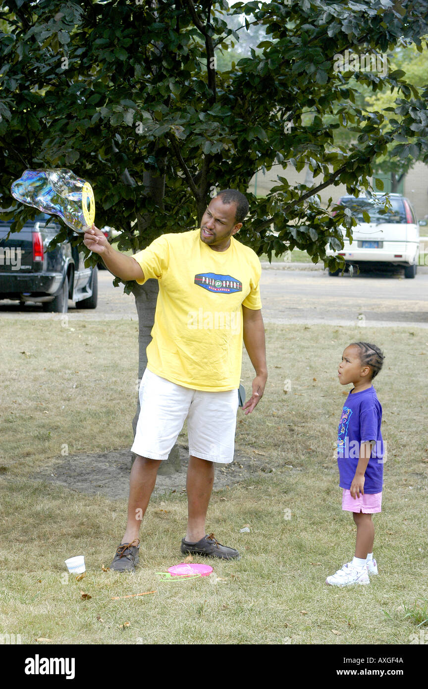 Father shows daughter how to work a bubble wand Stock Photo