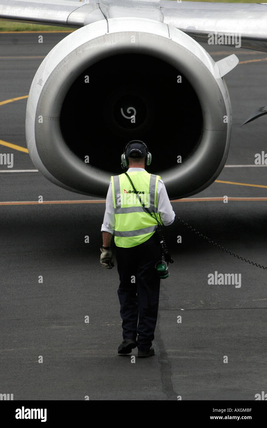 An airport traffic operator guides a Boeing 737 jet on the tarmac Stock Photo