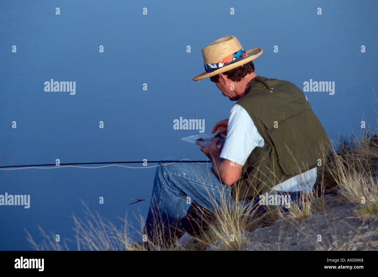 https://c8.alamy.com/comp/AXGW68/fly-fisherman-wearing-straw-hat-and-fishing-vest-selecting-fly-from-AXGW68.jpg