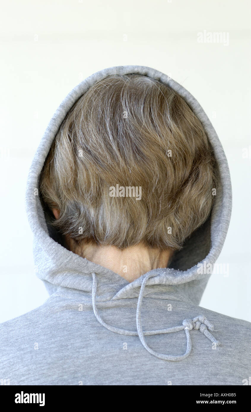 young female mental patient hiding by wearing a hooded gray sweatshirt backwards Stock Photo